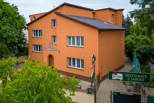 Oranžová budova Hotelu JAHODNICE v zeleni